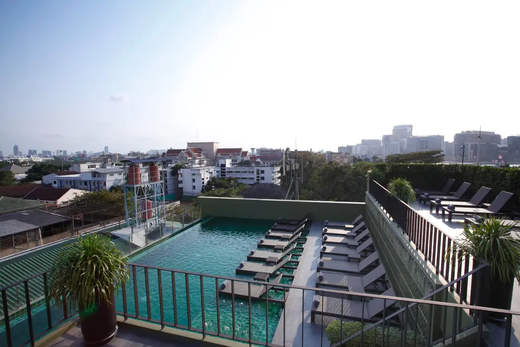 Daytime view across the rooftop pool and Bangkok skyline